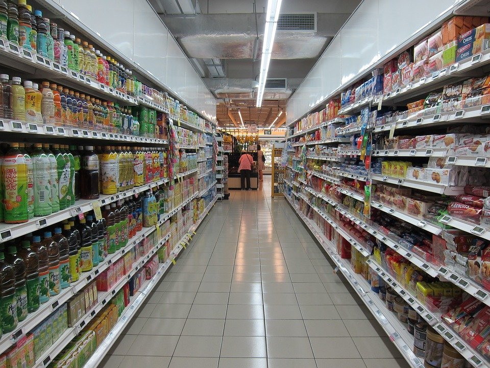 Grocery store aisle of soda and snacks.